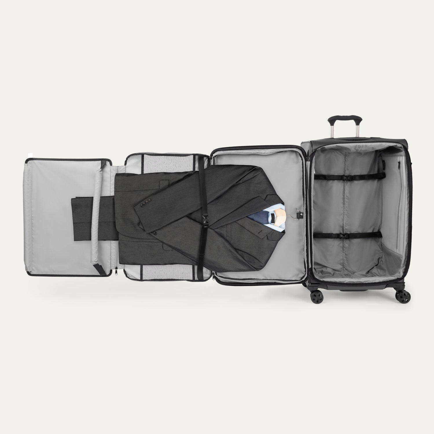 Open suitcase with suit displayed in fold out suiter compartment on white background