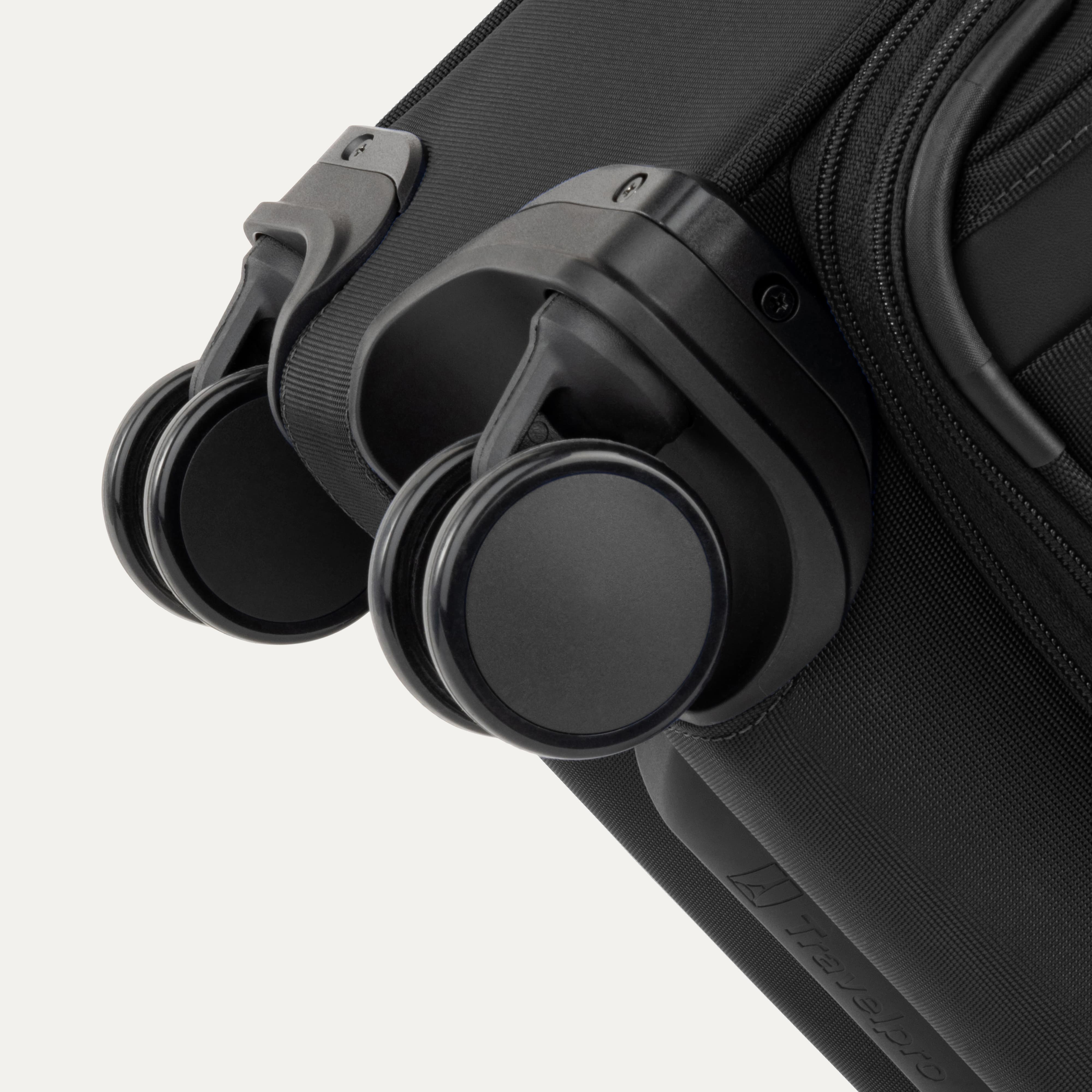 Close-up of Travelpro Versapack Spinner in Black, highlighting the Magnetically Self-Aligning Wheels for smooth mobility.