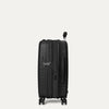 Une valise noire sur fond gris clair