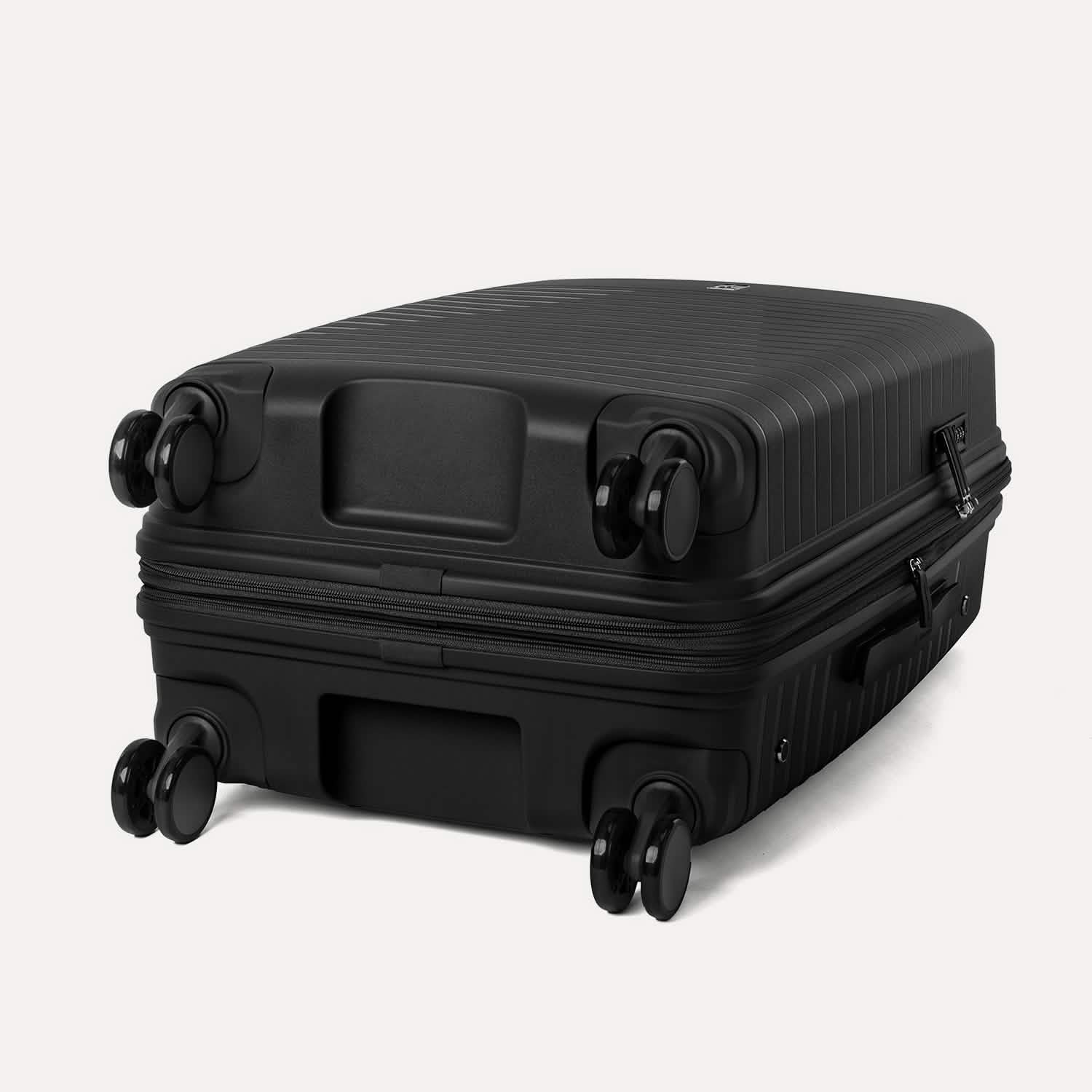 Valise noire à roulettes sur fond gris clair