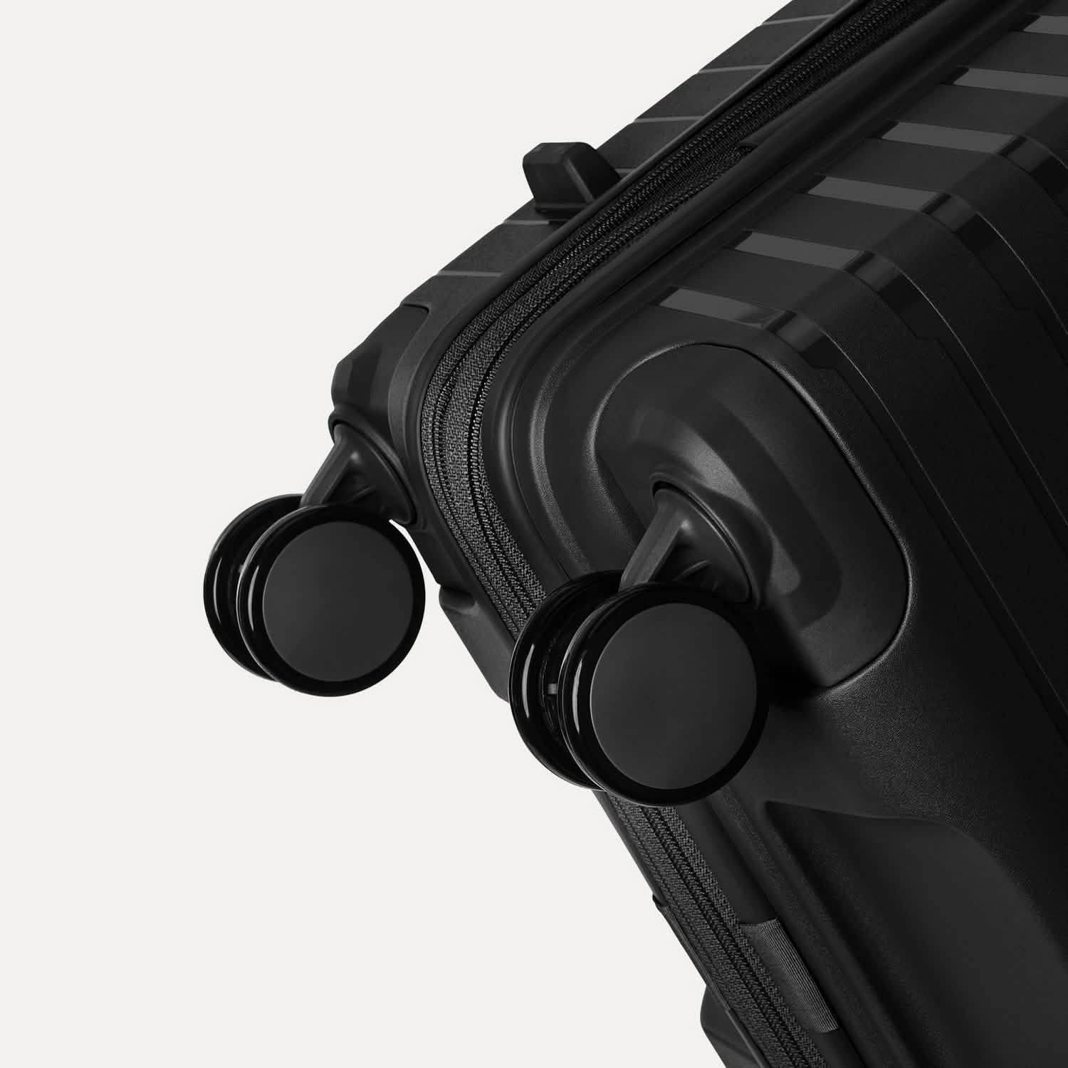 Valise noire à roulettes sur fond gris clair