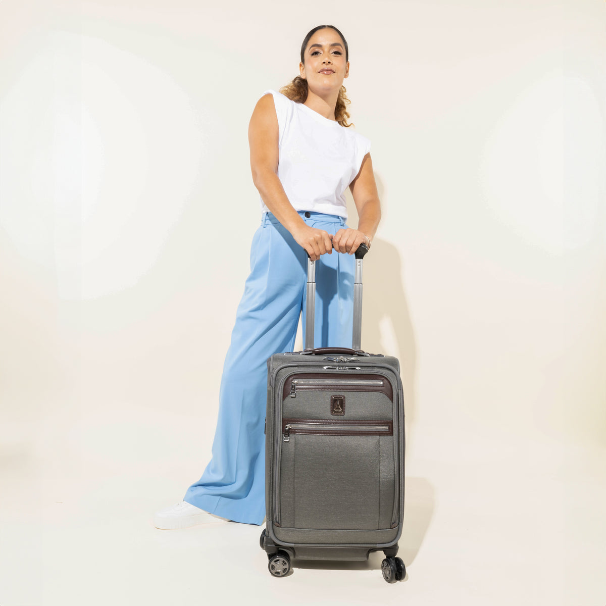 Person holding a vintage grey suitcase against a white background