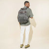 Person wearing a vintage grey backpack on a white background
