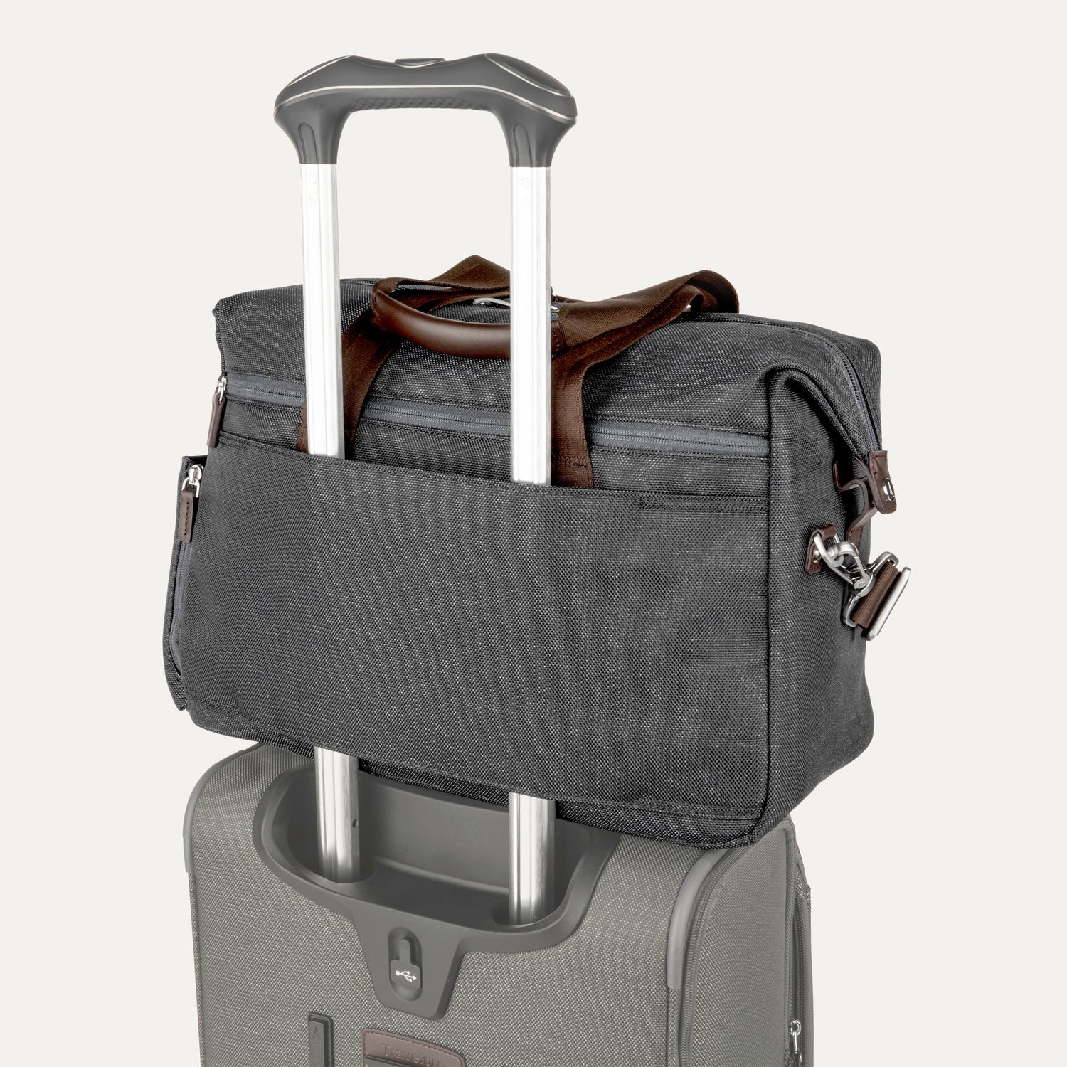 Grey tote secured over suitcase handle using rear strap, on a white background