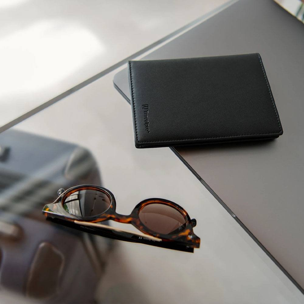 Airline guides, passport cover on glass table with sunglasses