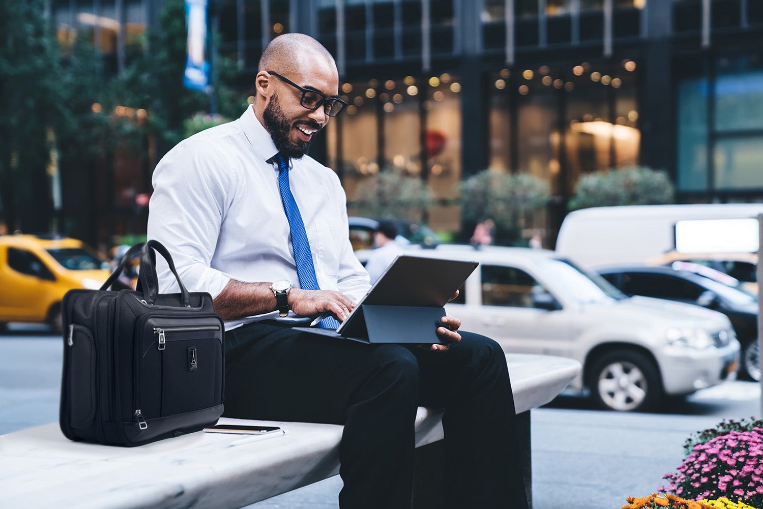 Man sitting outside of an office building, using a laptop