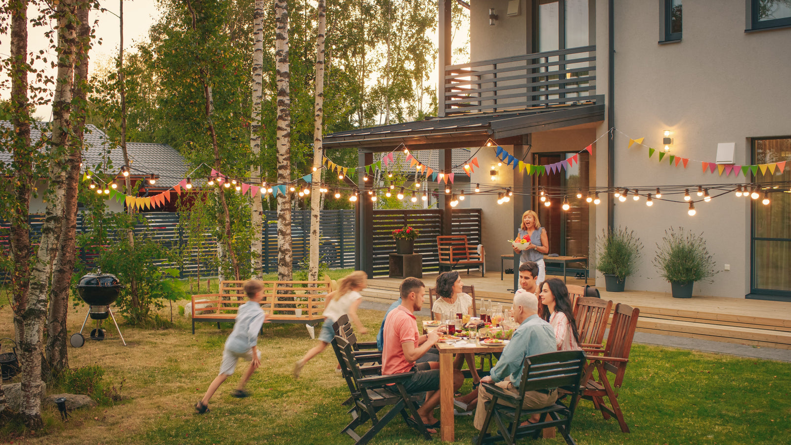 Family dining outdoors as kids play