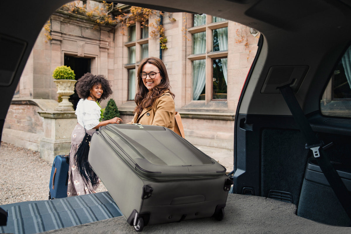 2 women unloading luggage from the trunk of a car