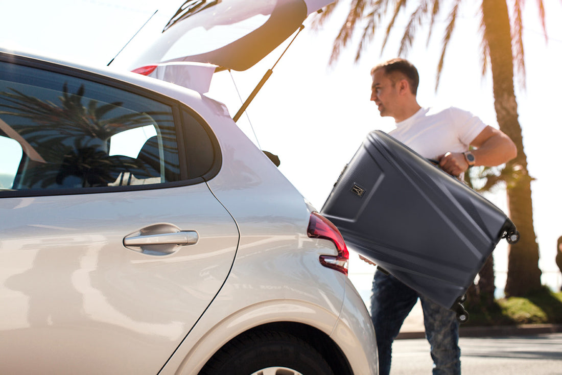 Man placing suitcase in the trunk of his car