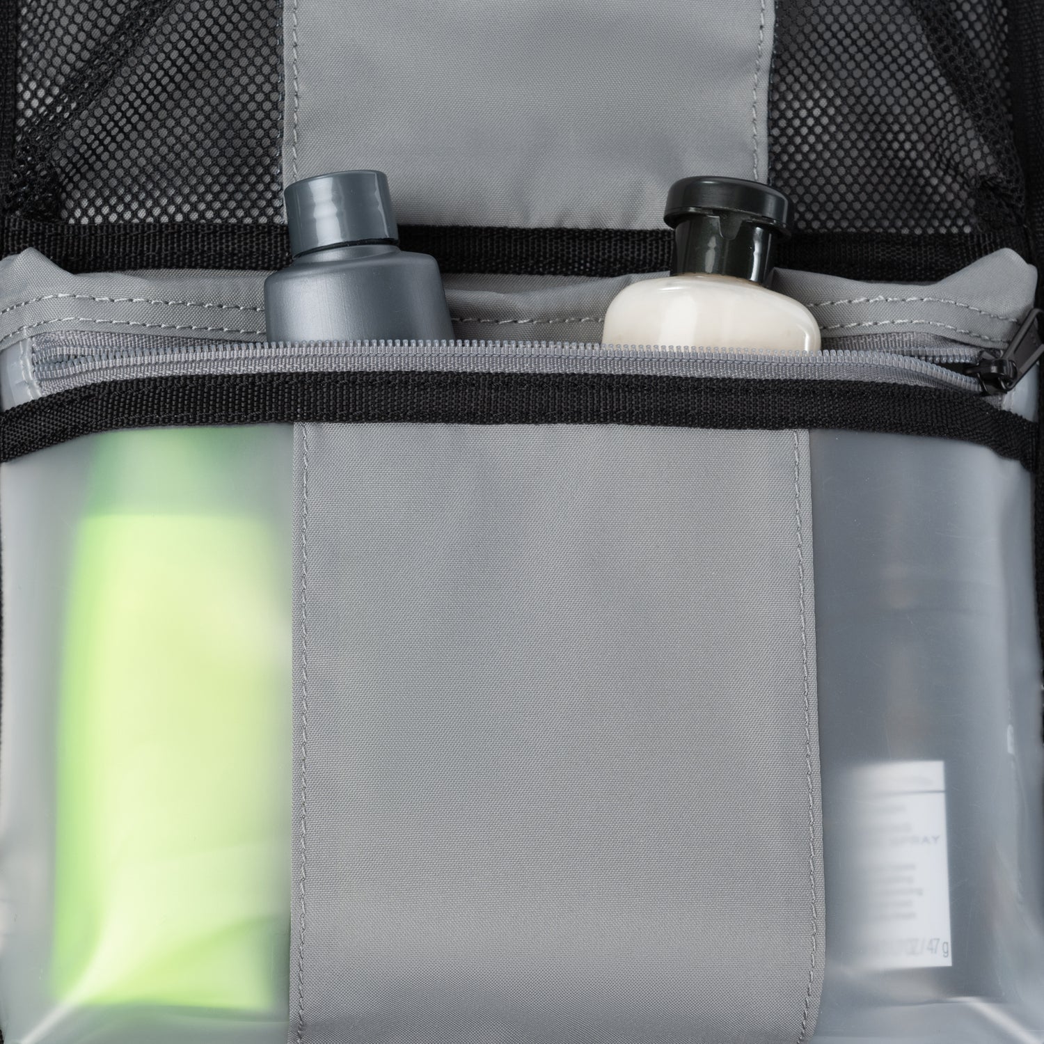Gros plan sur une poche intérieure à fermeture éclair contenant des flacons de produits de toilette partiellement visibles, dans une valise Travelpro.