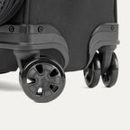Gros plan sur la valise Classic Travelpro Crew Classic Spinner en noir, mettant en avant ses roulettes pivotantes à 360°.

