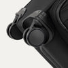 Close-up of Travelpro Versapack Spinner in Black, highlighting the Magnetically Self-Aligning Wheels for smooth mobility.
