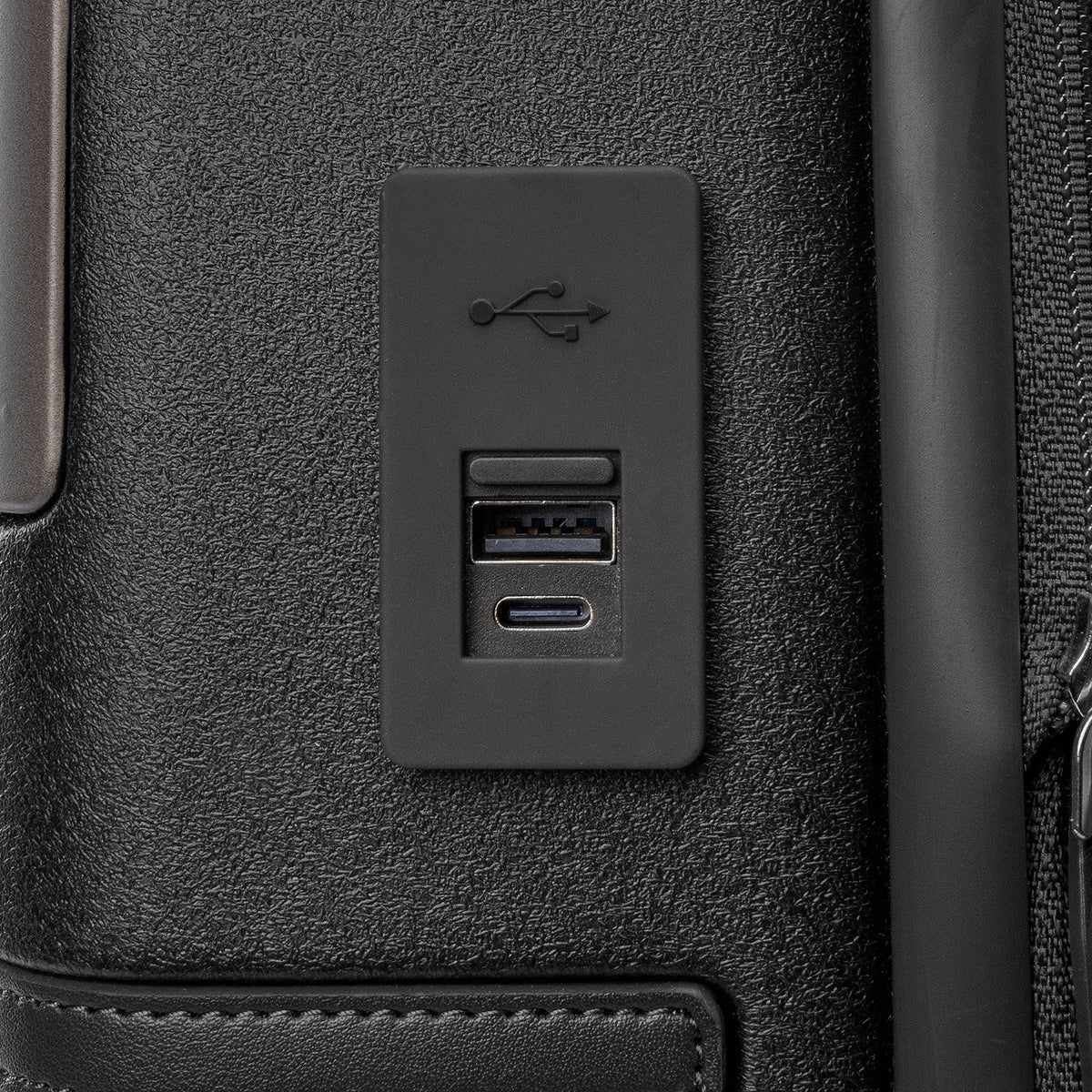 Close-up of the external USB-A and USB-C charging ports on the Travelpro Platinum Reserve Compact Carry-On Hardside Spinner in Black Dust