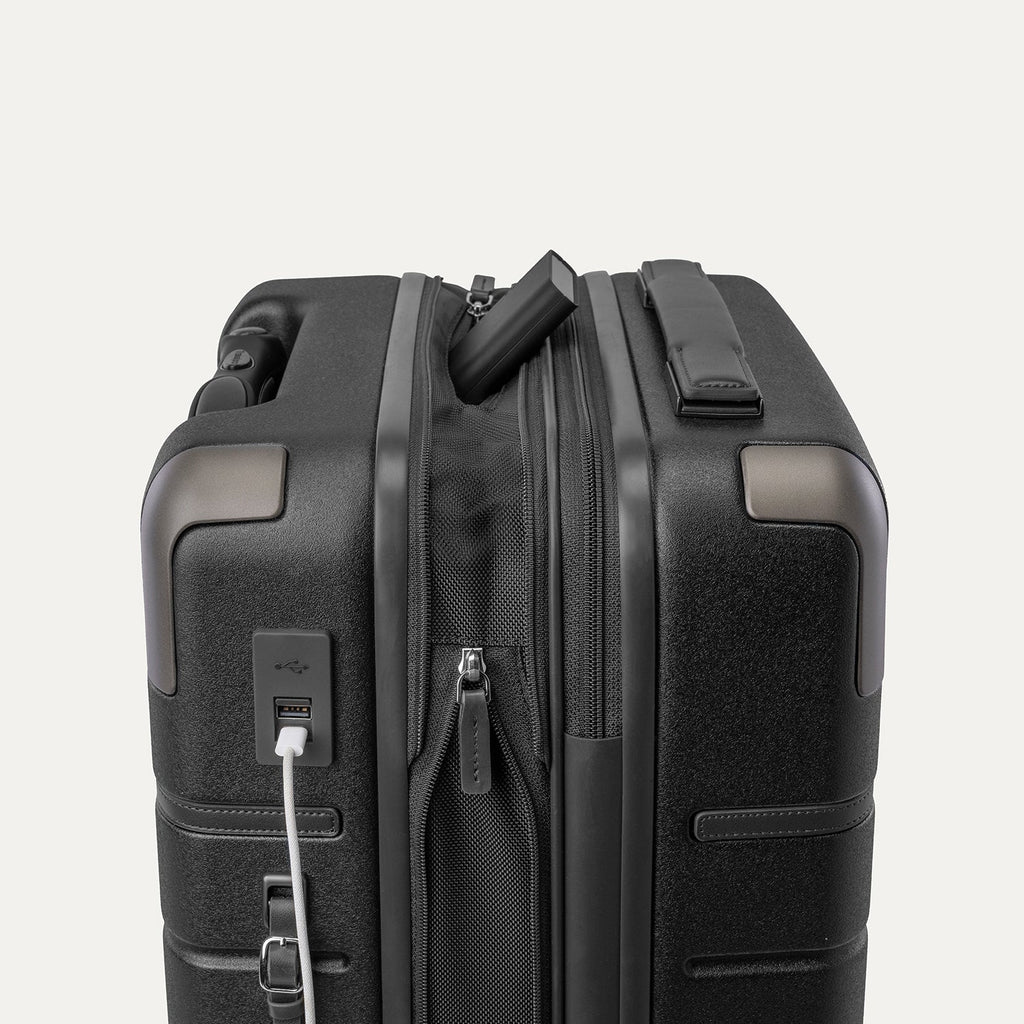 Charging cable plugged into the external USB port on the Travelpro Platinum Reserve Compact Carry-On Hardside Spinner in Black Dust