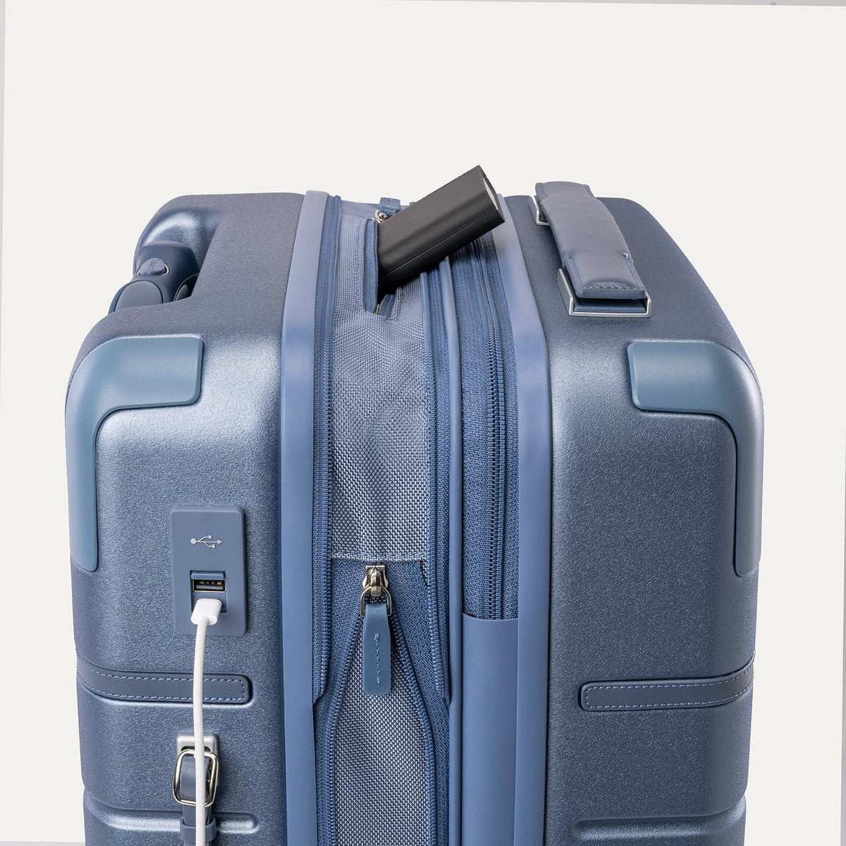 Charging cable plugged into the external USB port on the Travelpro Platinum Reserve Compact Carry-On Hardside Spinner in Steel Blue