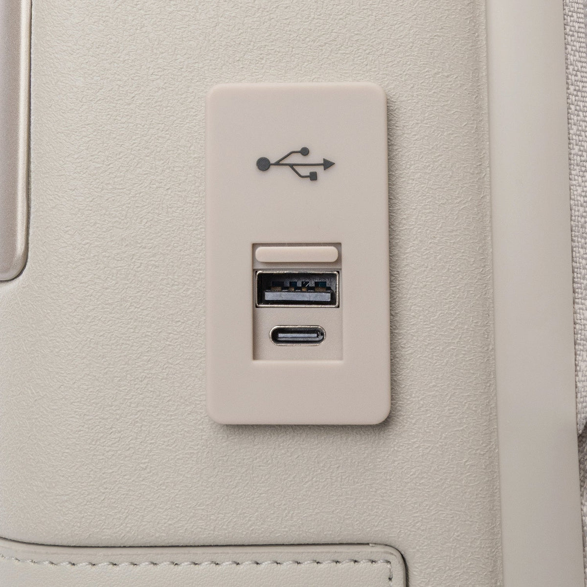 Close-up of the external USB-A and USB-C charging ports on the Travelpro Platinum Reserve Compact Carry-On Hardside Spinner in Sandstone