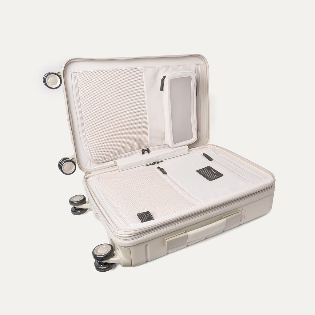 Open interior of the Travelpro Platinum Reserve Compact Carry-On Hardside Spinner in Sandstone showing the zippered divider panel and dedicated pockets