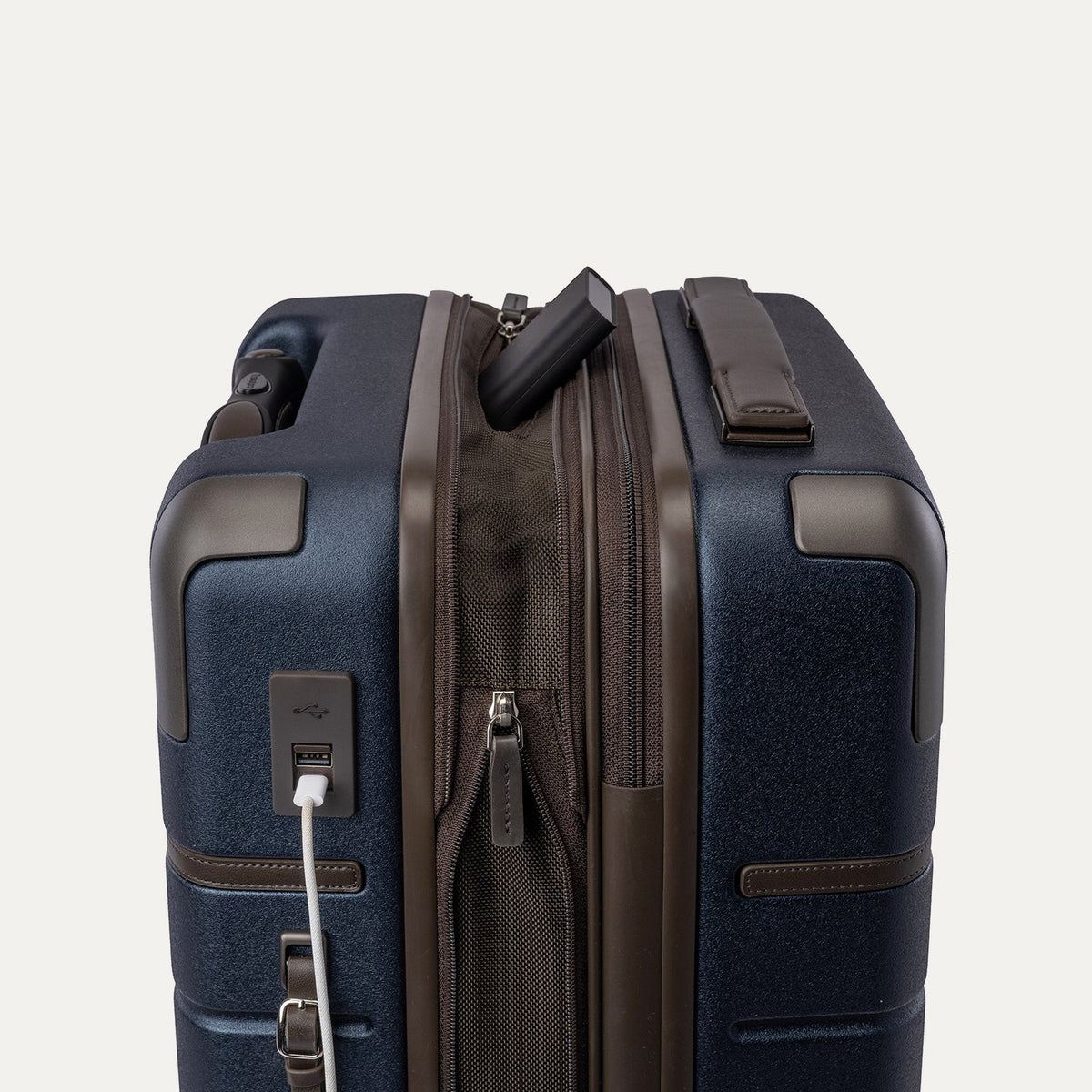 Charging cable plugged into the external USB port on the Travelpro Platinum Reserve Compact Carry-On Hardside Spinner in Midnight Trail