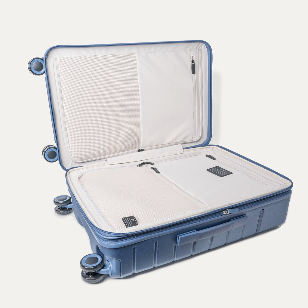 Open interior of the Travelpro Platinum Reserve Medium Check-In Hardside Spinner in Steel Blue showing the zippered divider panel and dedicated pockets