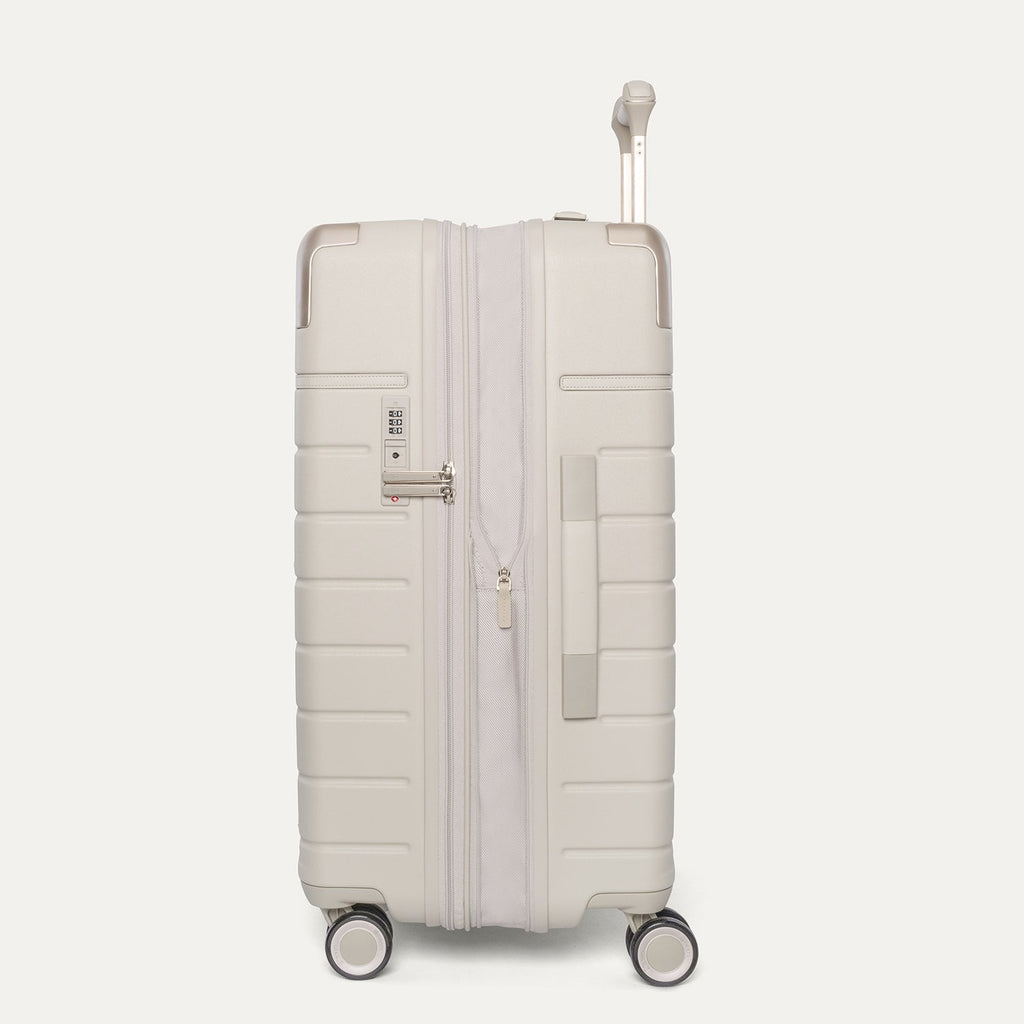 Side profile of the Travelpro Platinum Reserve Medium Check-In Hardside Spinner in Sandstone, expanded for extra packing space