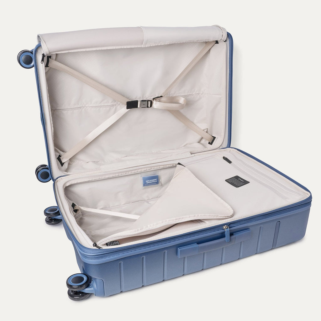 Open interior of the Travelpro Platinum Reserve Large Check-In Hardside Spinner in Steel Blue with hold-down straps