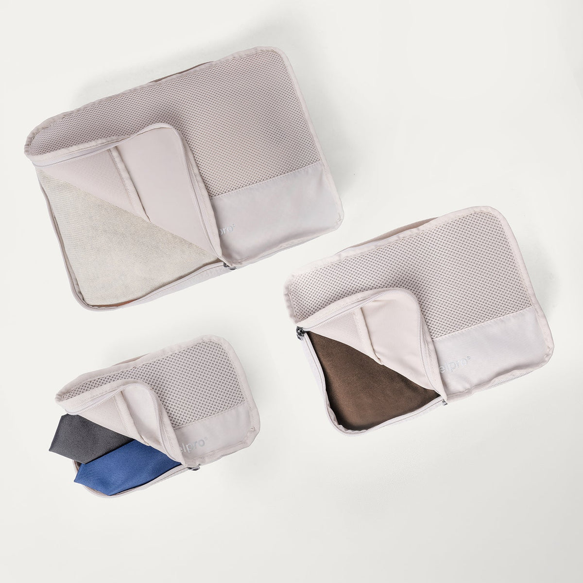 Packing cubes included with the Travelpro Platinum Reserve Large Check-In Hardside Spinner in Sandstone, shown open with folded clothing