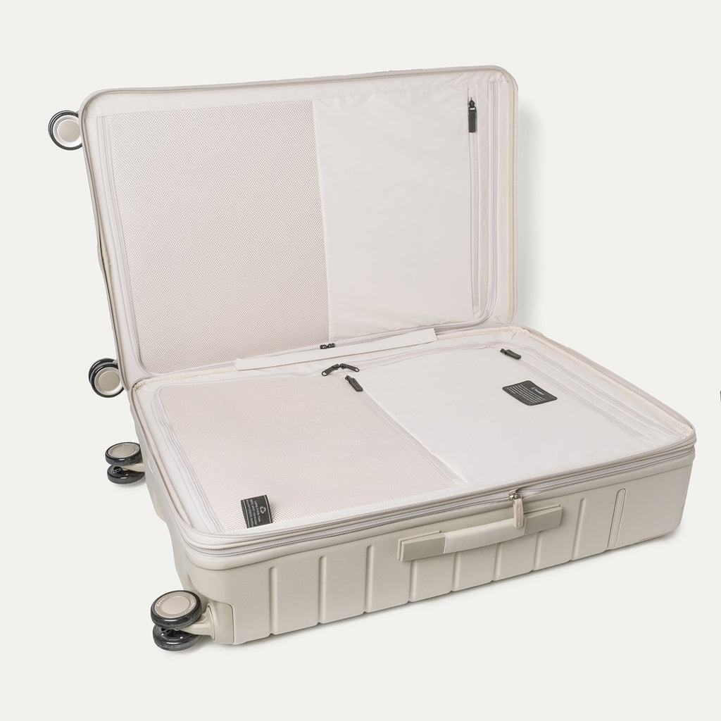 Open interior of the Travelpro Platinum Reserve Large Check-In Hardside Spinner in Sandstone showing the zippered divider panel and dedicated pockets