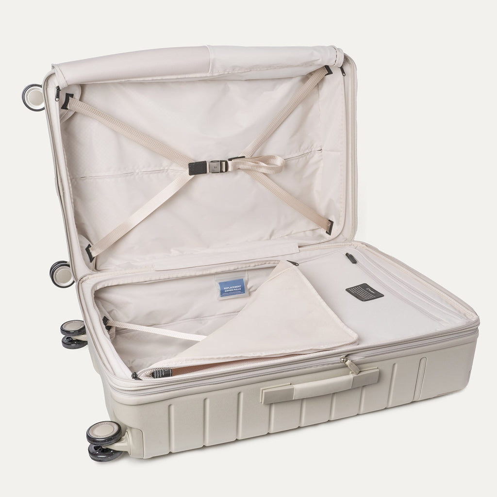 Open interior of the Travelpro Platinum Reserve Large Check-In Hardside Spinner in Sandstone with hold-down straps