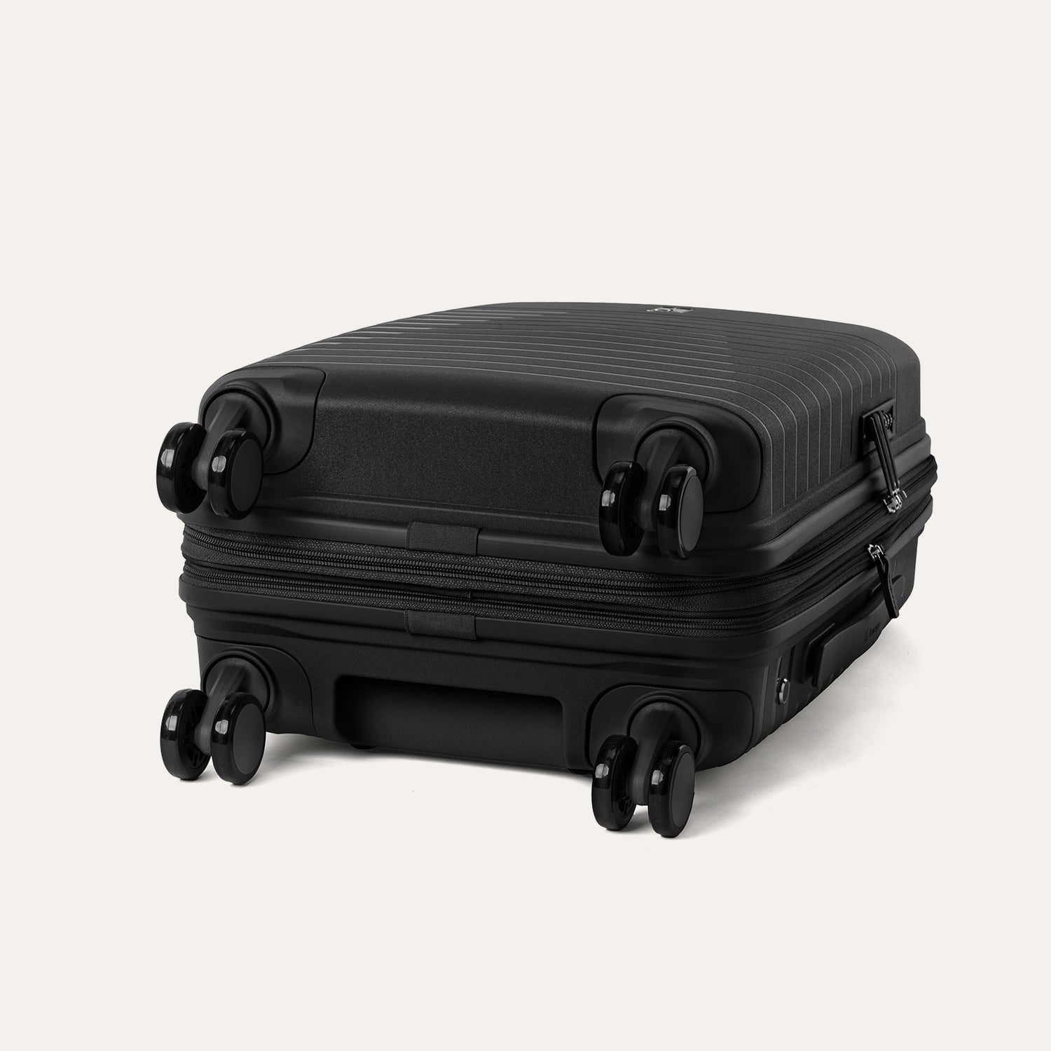 Valise noire à roulettes sur fond gris clair