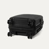 Valise noire à roulettes sur fond gris clair