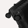 Valise noire à roulettes sur fond gris clair