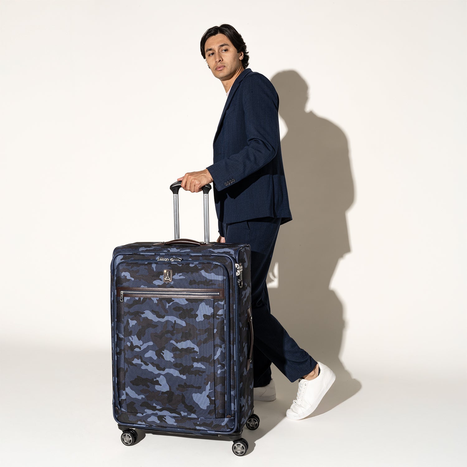 Traveler holding the Travelpro Platinum Elite Large Check-In Spinner in Camouflage