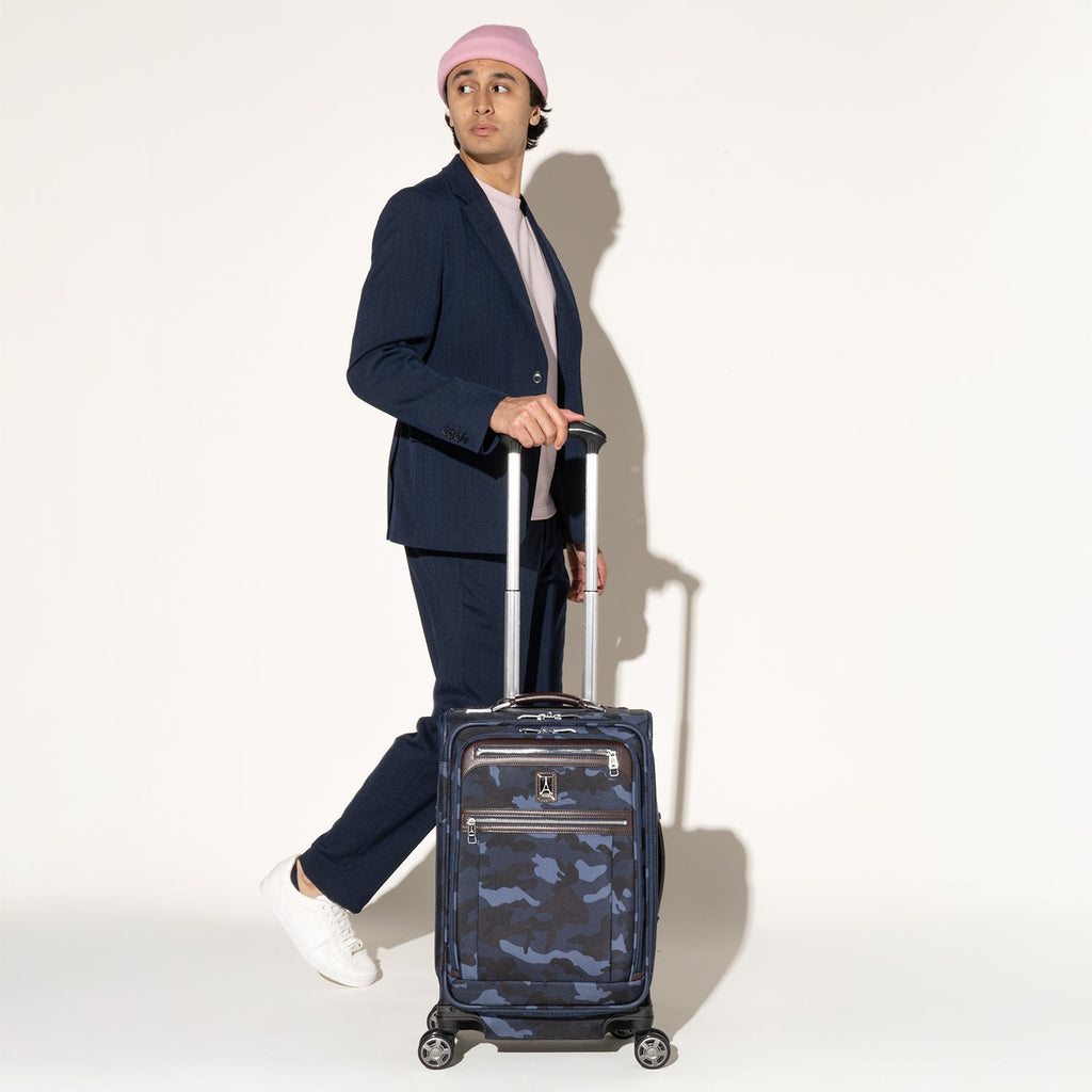 Traveler standing with the Travelpro Platinum Elite Carry-On Expandable Spinner in Camouflage
