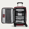 Une valise rouge ouverte, avec une sangle de rangement, posée sur un fond blanc