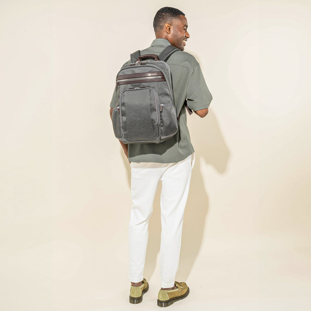Person wearing a vintage grey business backpack on a white background