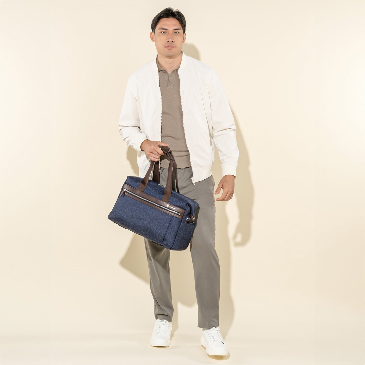 Person holding a true navy tote with brown handles on a white background