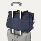 True navy tote secured over suitcase handle using rear strap, on a white background
