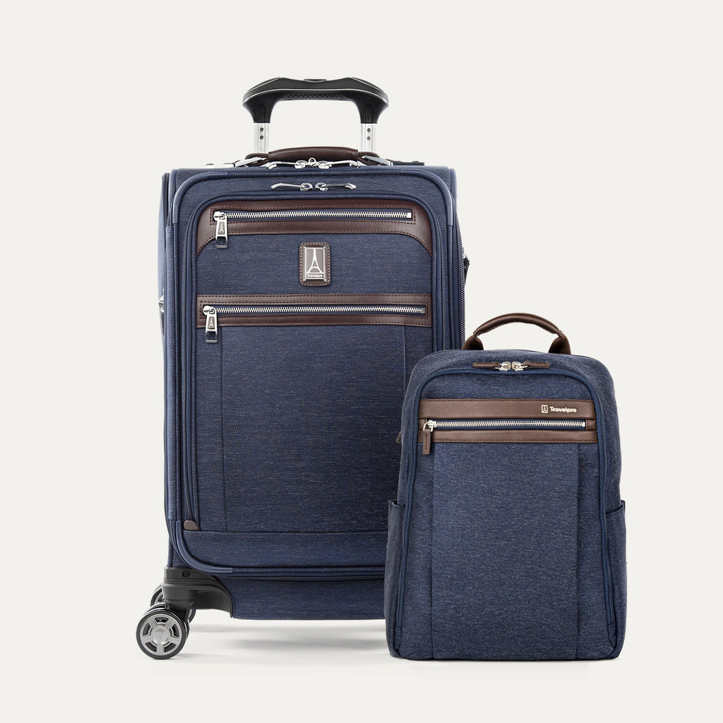 A set of navy blue travel luggage, including an expandable carry-on spinner and a slim backpack, with brown leather accents.